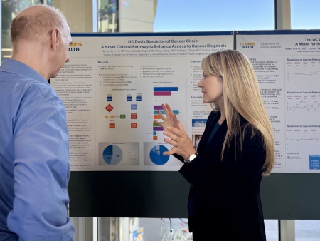 Dr. Erin Noren presents a poster at the 2025 Internal Medicine Research Symposium to a man in a blue shirt.